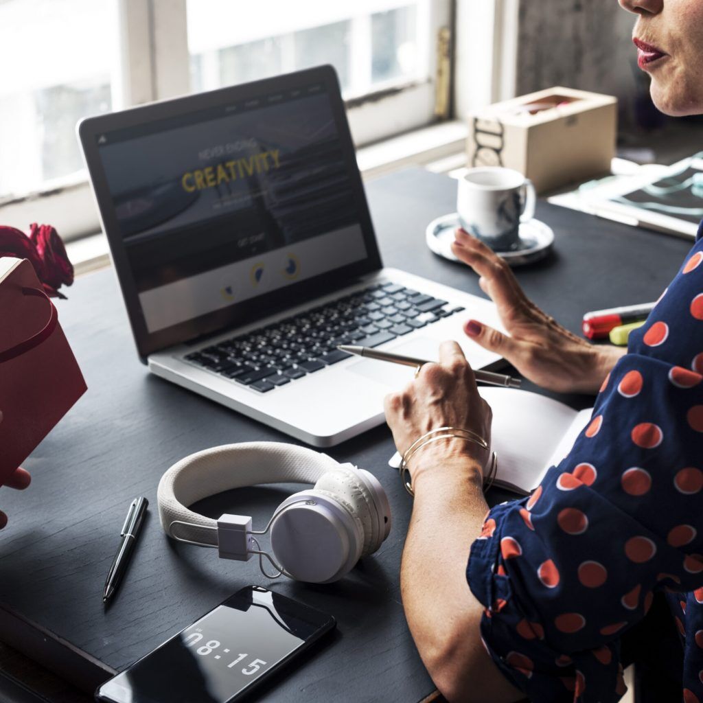 Woman Talking with Colleague and Using Laptop